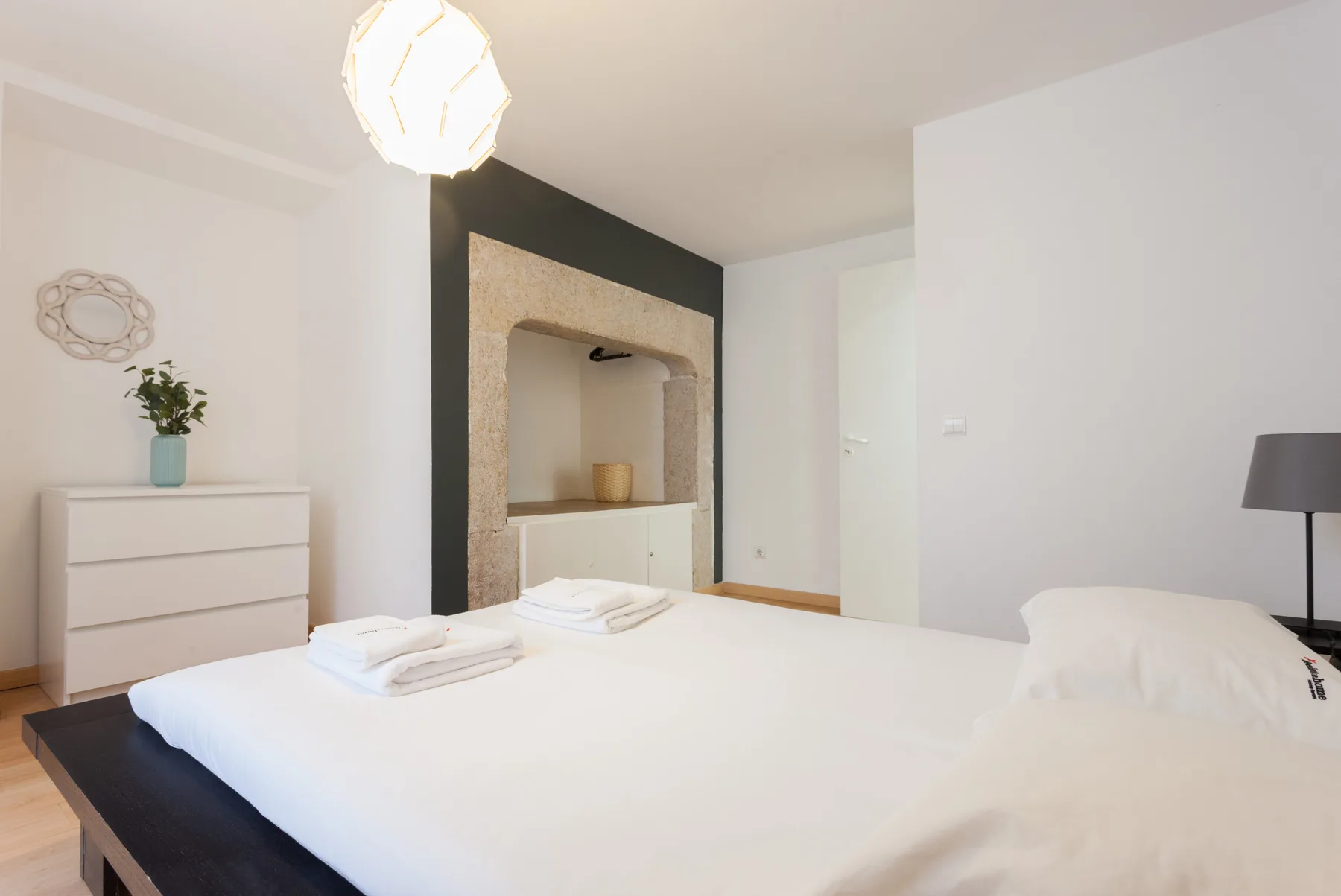 Un dormitorio luminoso con una cama bien hecha y una cómoda blanca.