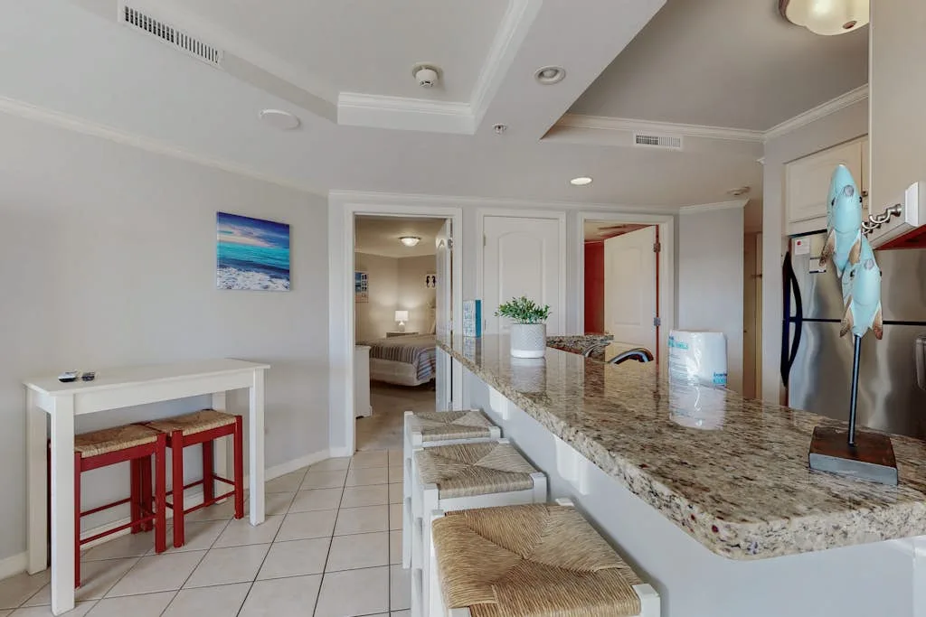 A bright kitchen with a long stone counter and stools.