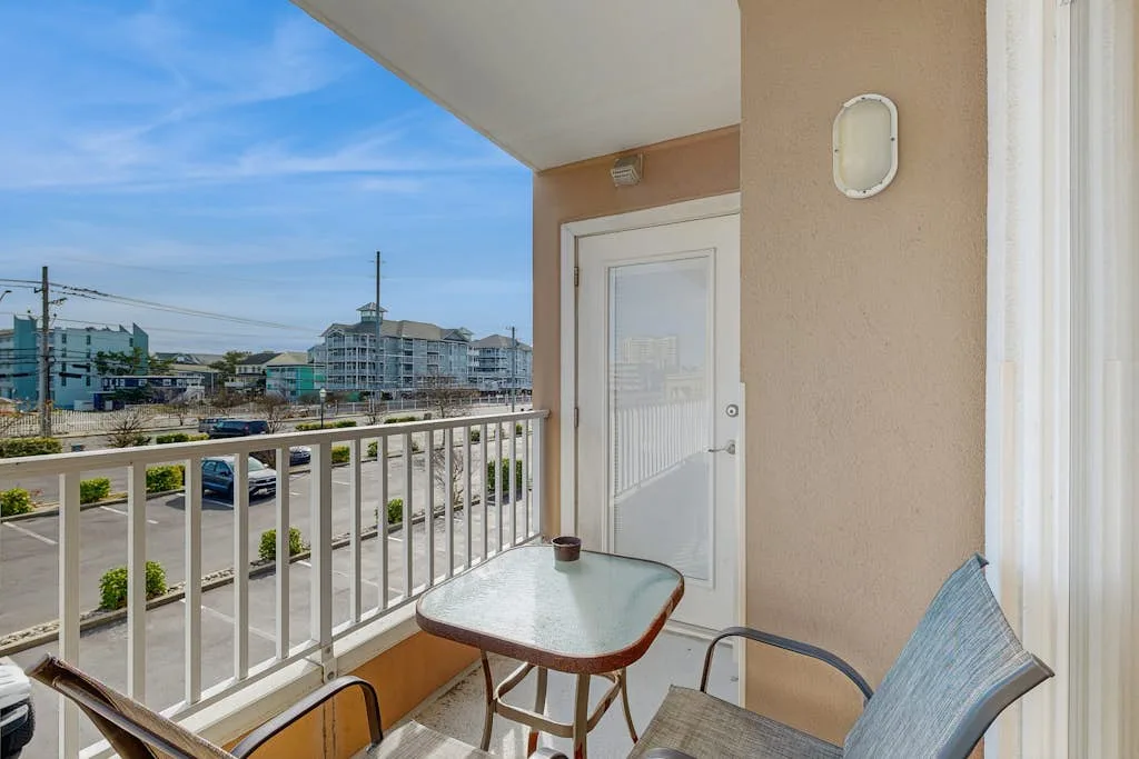 A small balcony with a table and chairs overlooks nearby buildings.
