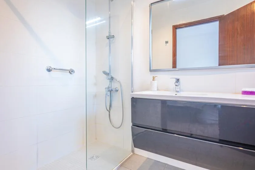 A bright bathroom with a glass shower and a wide vanity beneath a mirror.