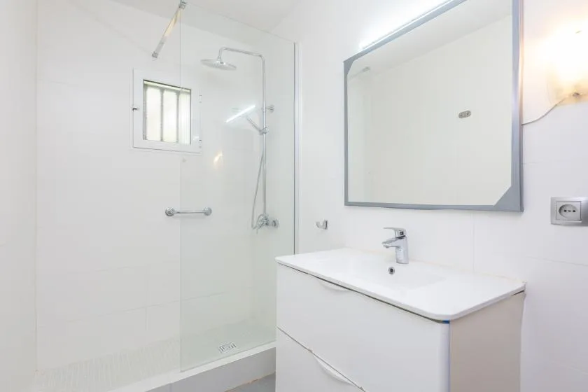 A bright bathroom with a glass shower and a white sink vanity.