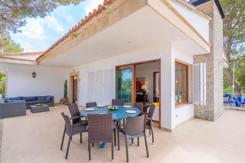A covered patio with a dining table and seating beside the house.