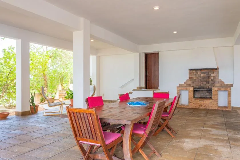 A bright dining area with a wooden table and pink chairs beside large windows.