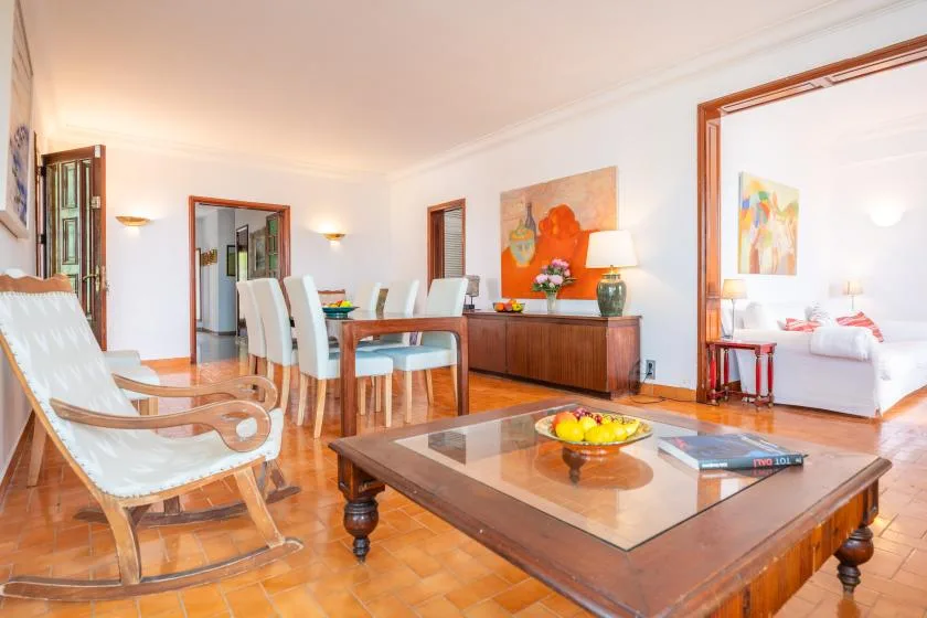 A bright living and dining area with a wooden table and seating.