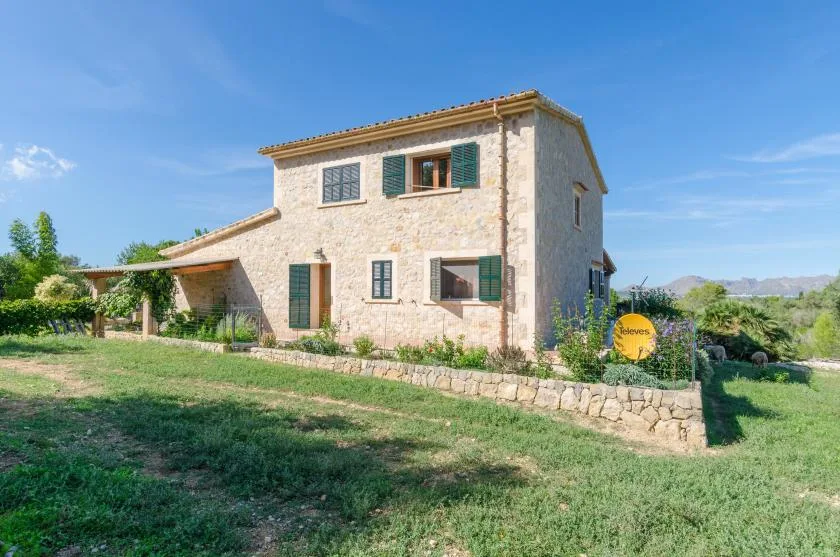 A stone house stands in a grassy yard beneath a clear sky.