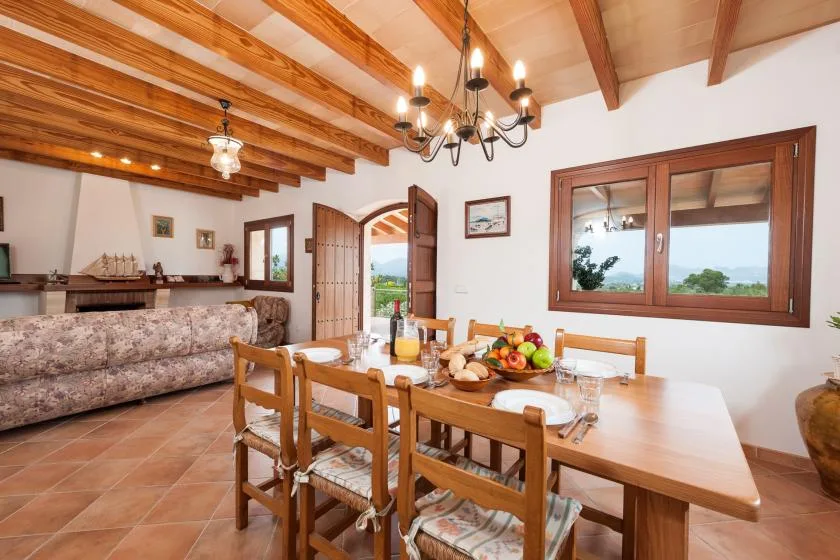 A dining area with a wooden table and chairs beneath exposed ceiling beams.