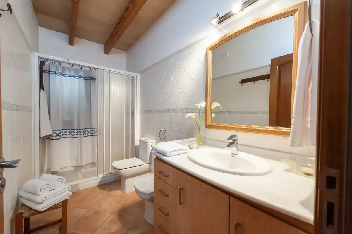 A bathroom with a shower, toilet, and vanity beneath a large mirror.