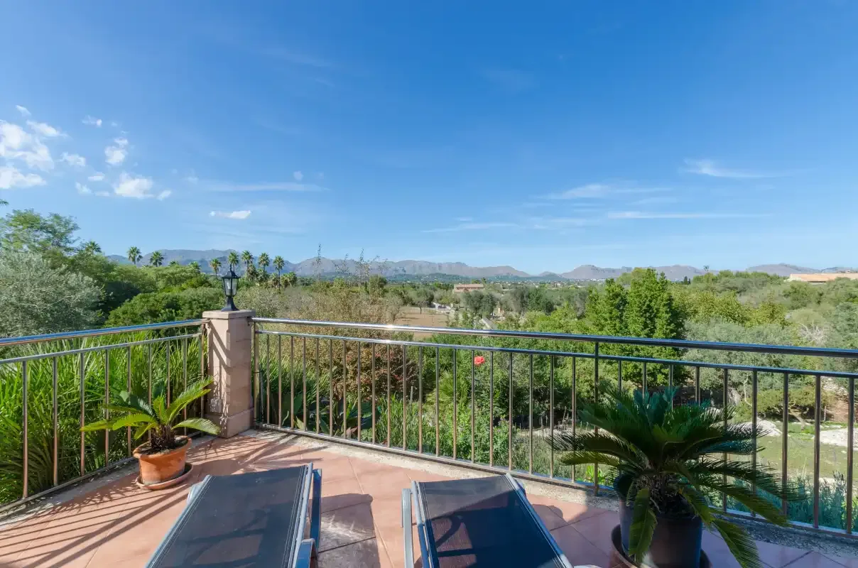 A tiled terrace overlooks green vegetation and distant hills.