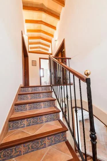 A tiled staircase with a dark metal railing rises through a bright interior.