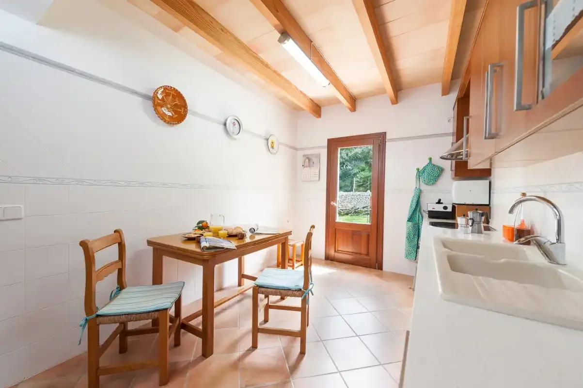 A bright kitchen with a wooden dining table and sink.
