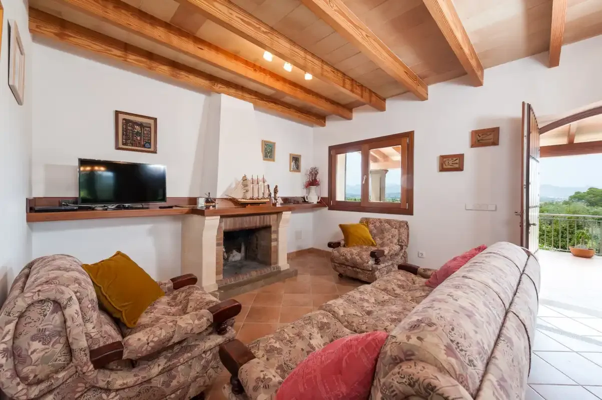 A living room with patterned seating, a television, and a fireplace.
