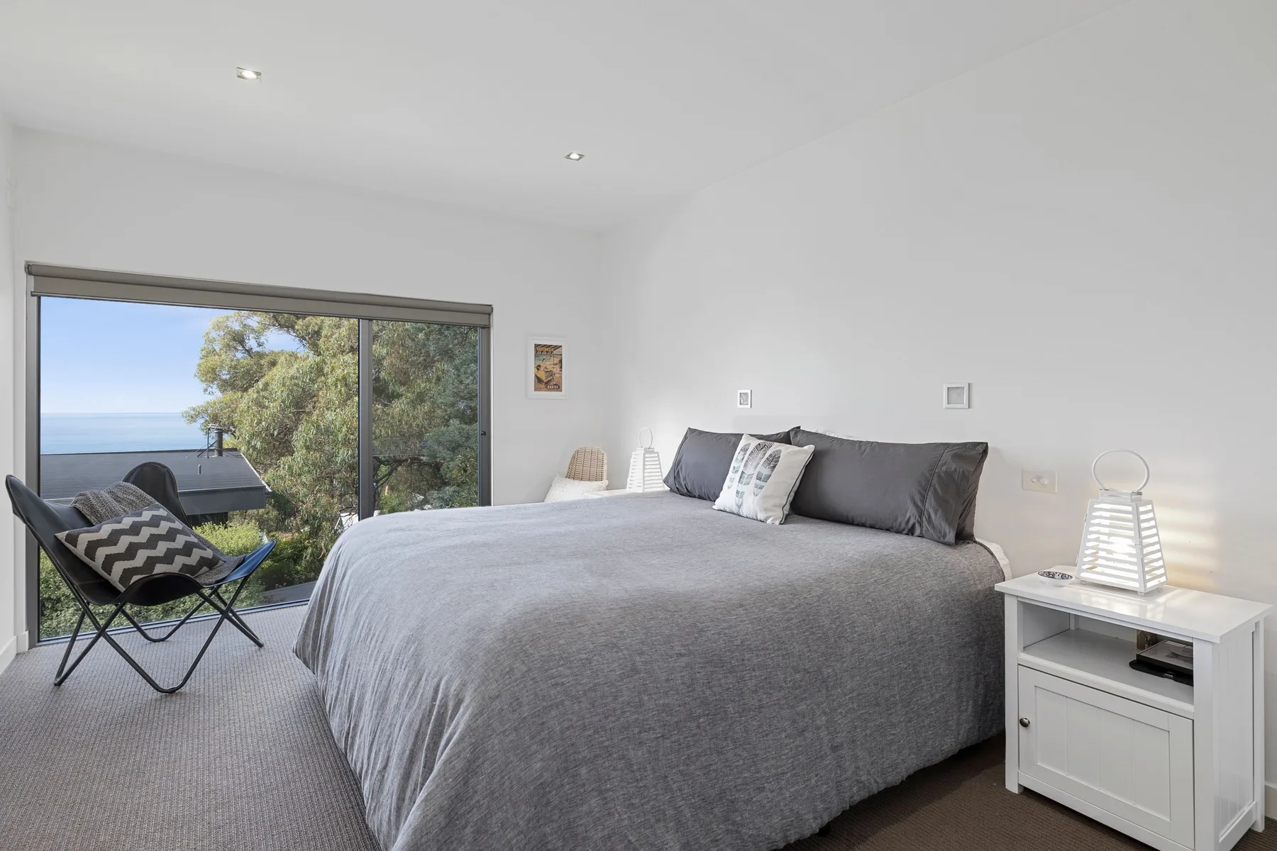 A bright bedroom with a large bed beside a sliding glass door.