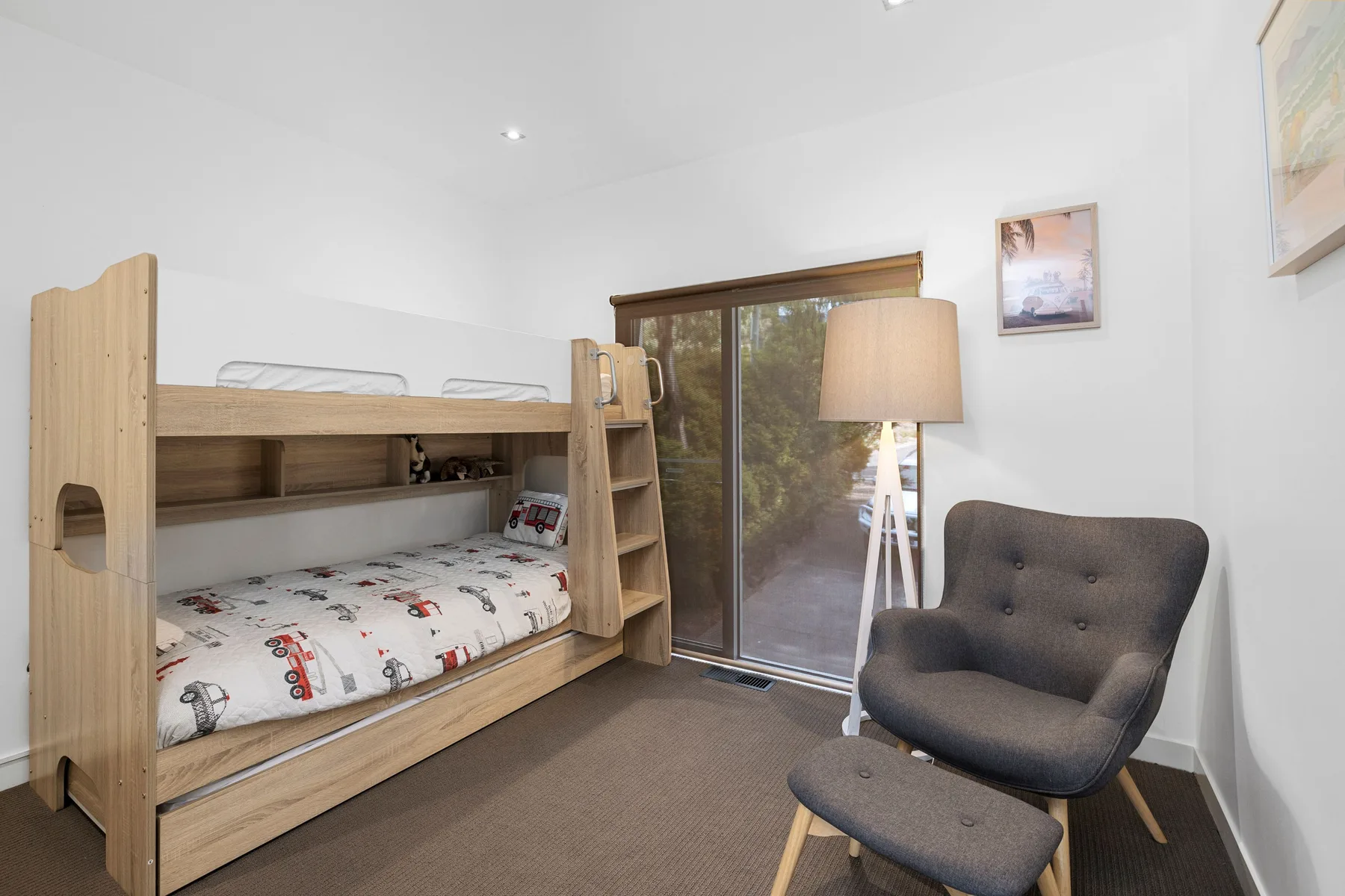 A bedroom with a wooden bunk bed and a large window overlooking trees.
