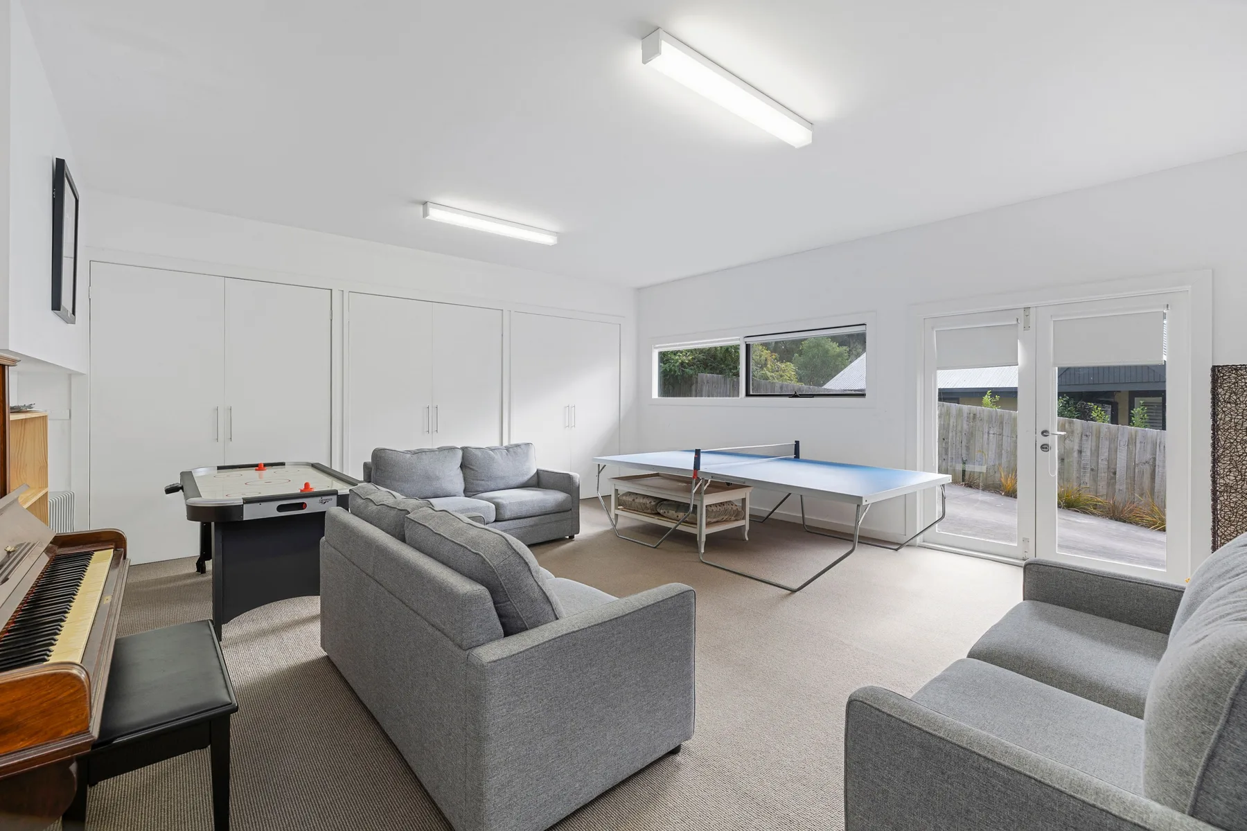 A bright recreation room with seating, a table tennis table, and a pool table.