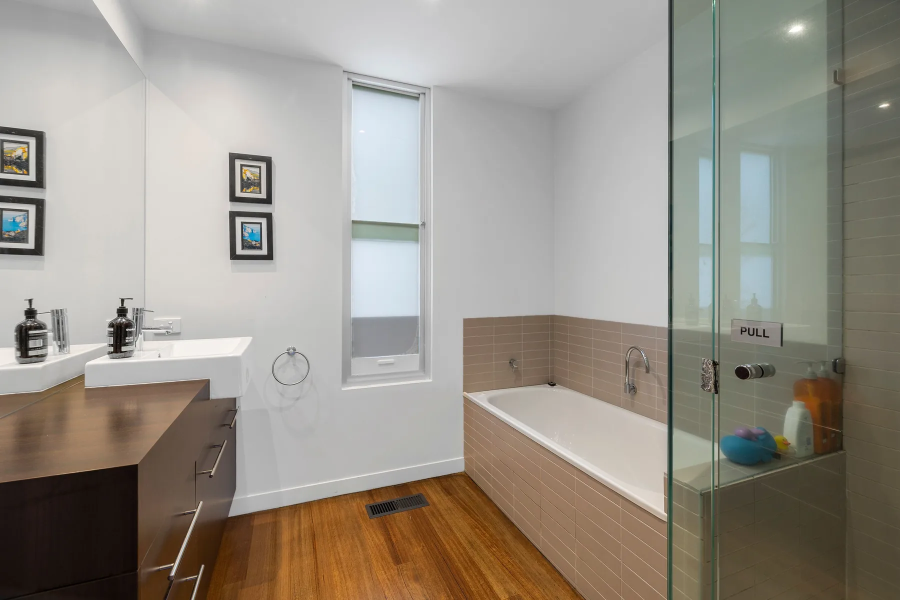 A bright bathroom with a bathtub, glass shower, and wooden vanity.
