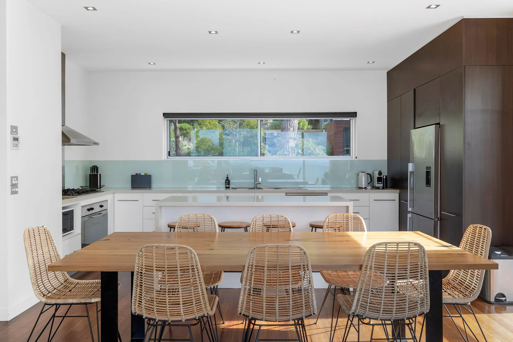 Una cocina luminosa con comedor, una mesa larga de madera y una ventana amplia.
