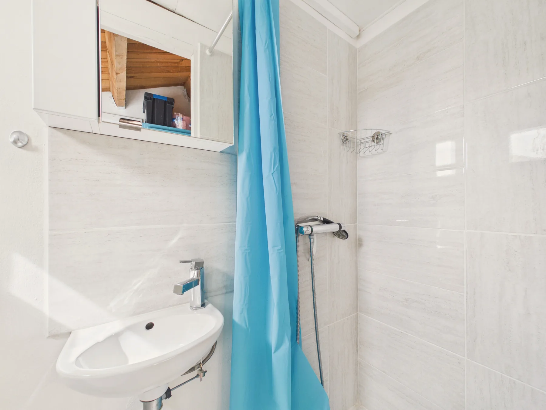 A tiled bathroom with a sink and a blue shower curtain.