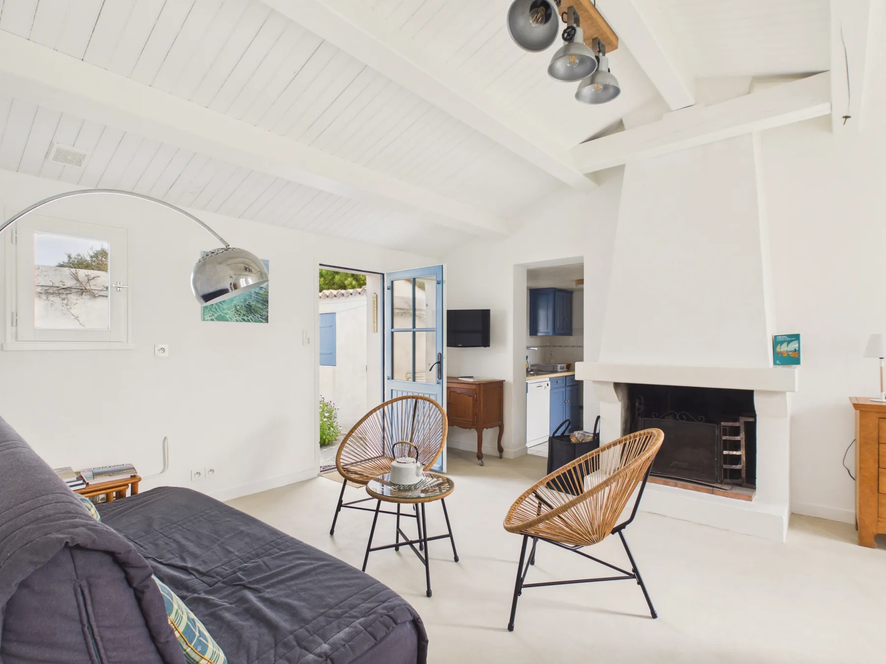 A bright living room with seating, a fireplace, and an open doorway.