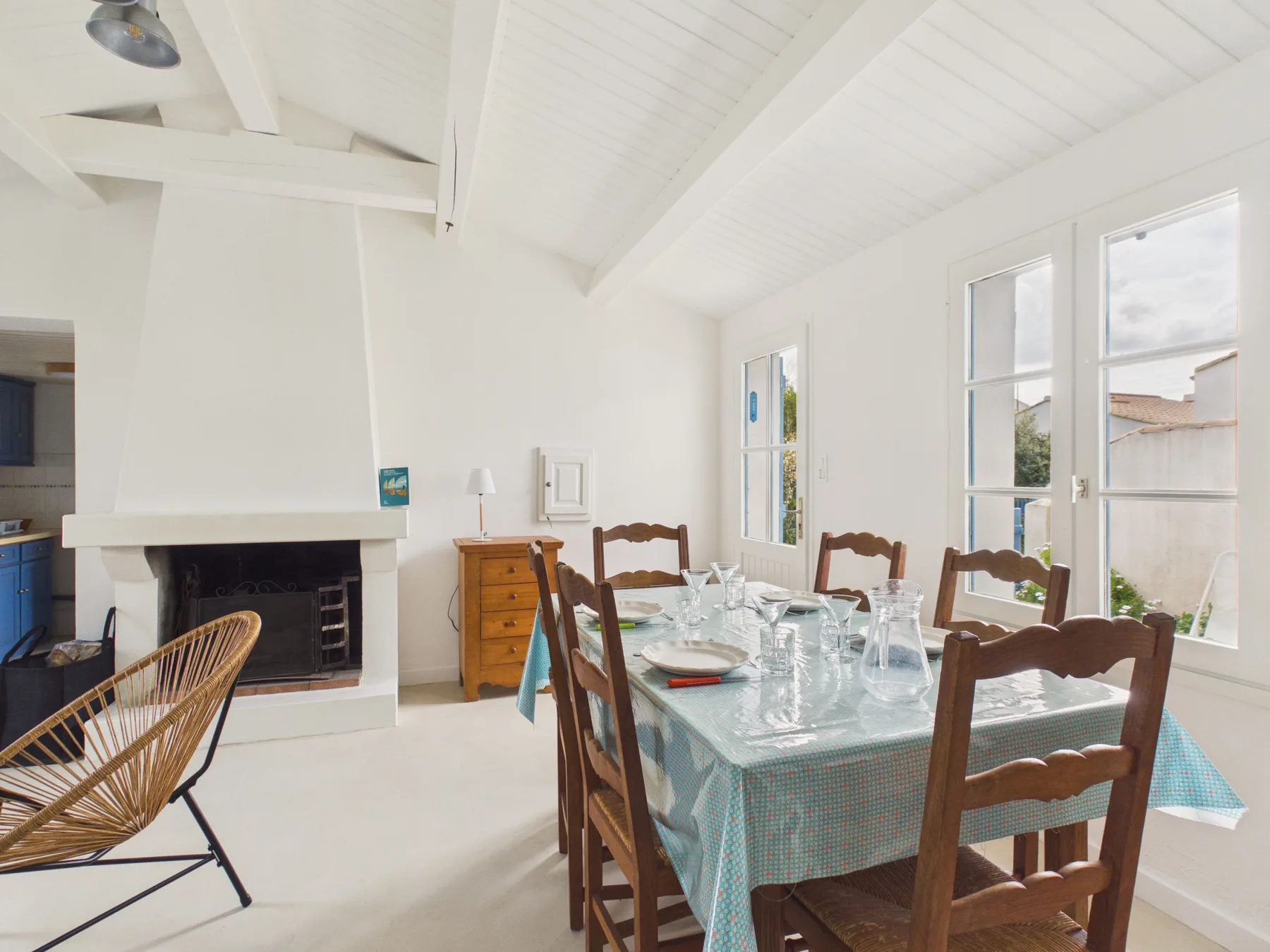 A bright dining area with a set table beside a fireplace.