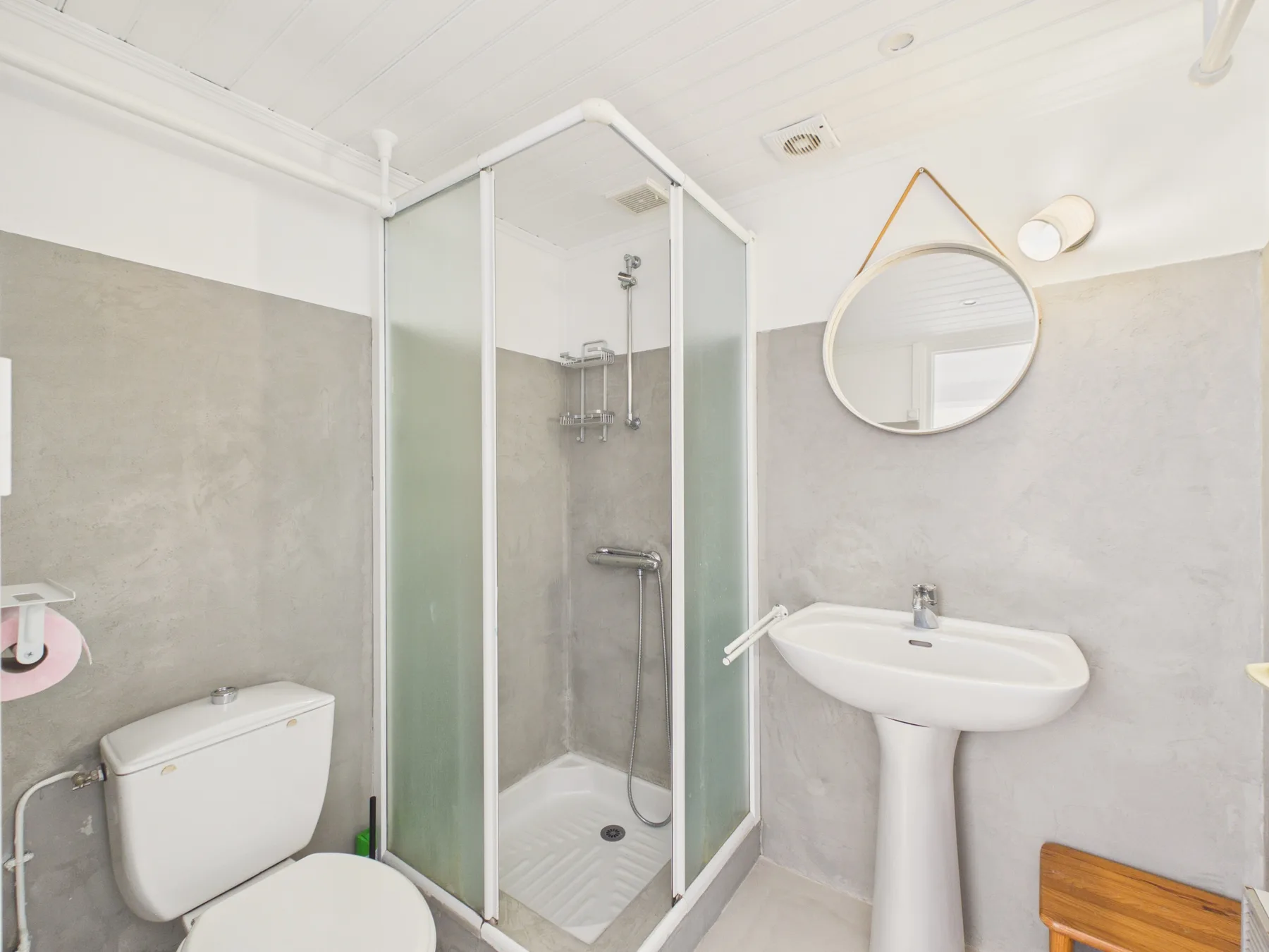 A bathroom with a glass shower, pedestal sink, and toilet.