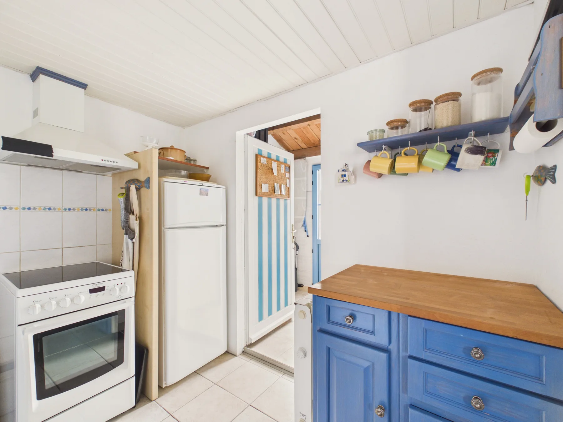 A compact kitchen with a white stove and blue cabinetry.