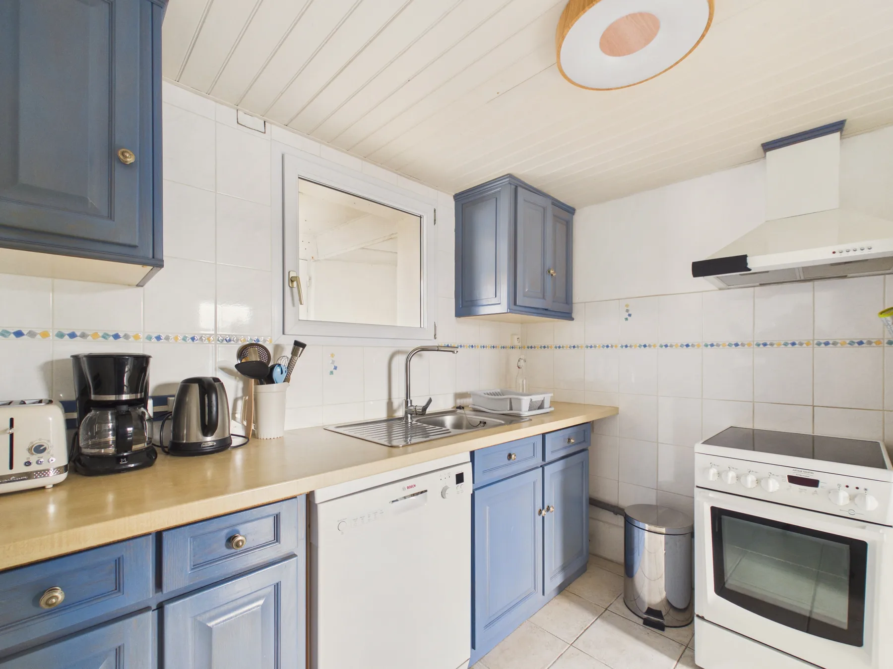 A bright kitchen with blue cabinets, a sink, and a stove.