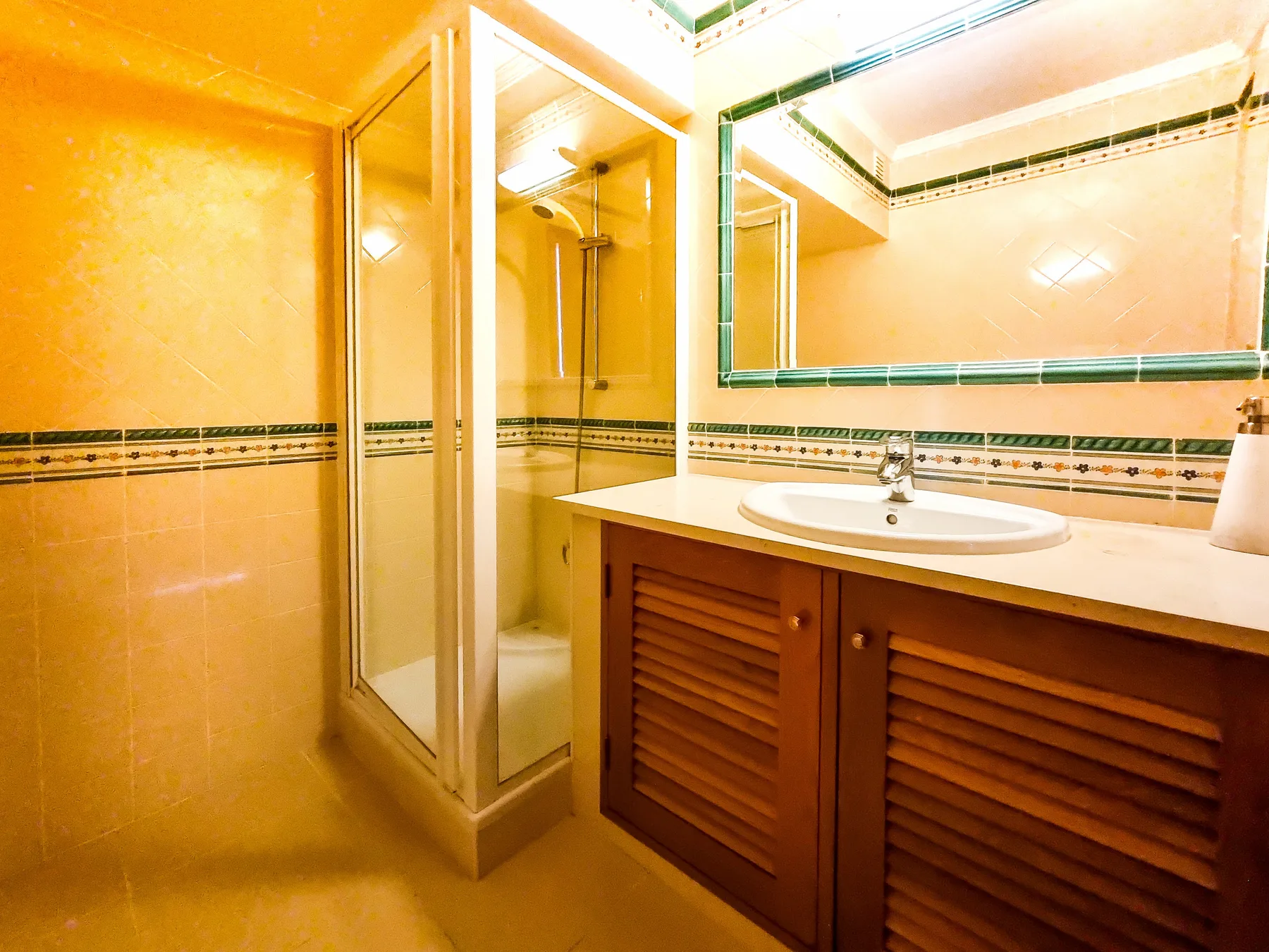 A tiled bathroom with a glass shower and a sink vanity.