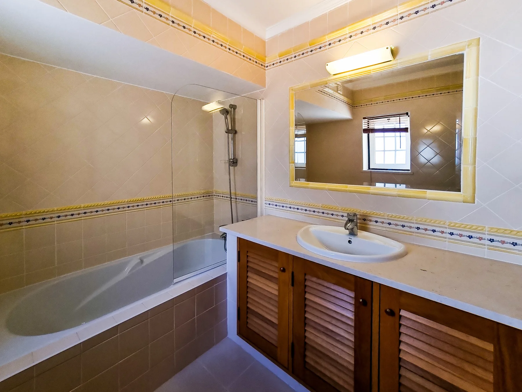 A bathroom with a bathtub, shower, and vanity beneath a large mirror.