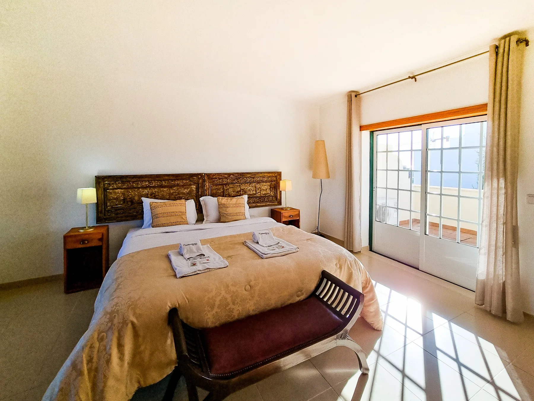 Un dormitorio con una cama grande y puertas corredizas de vidrio que dan a un balcón.