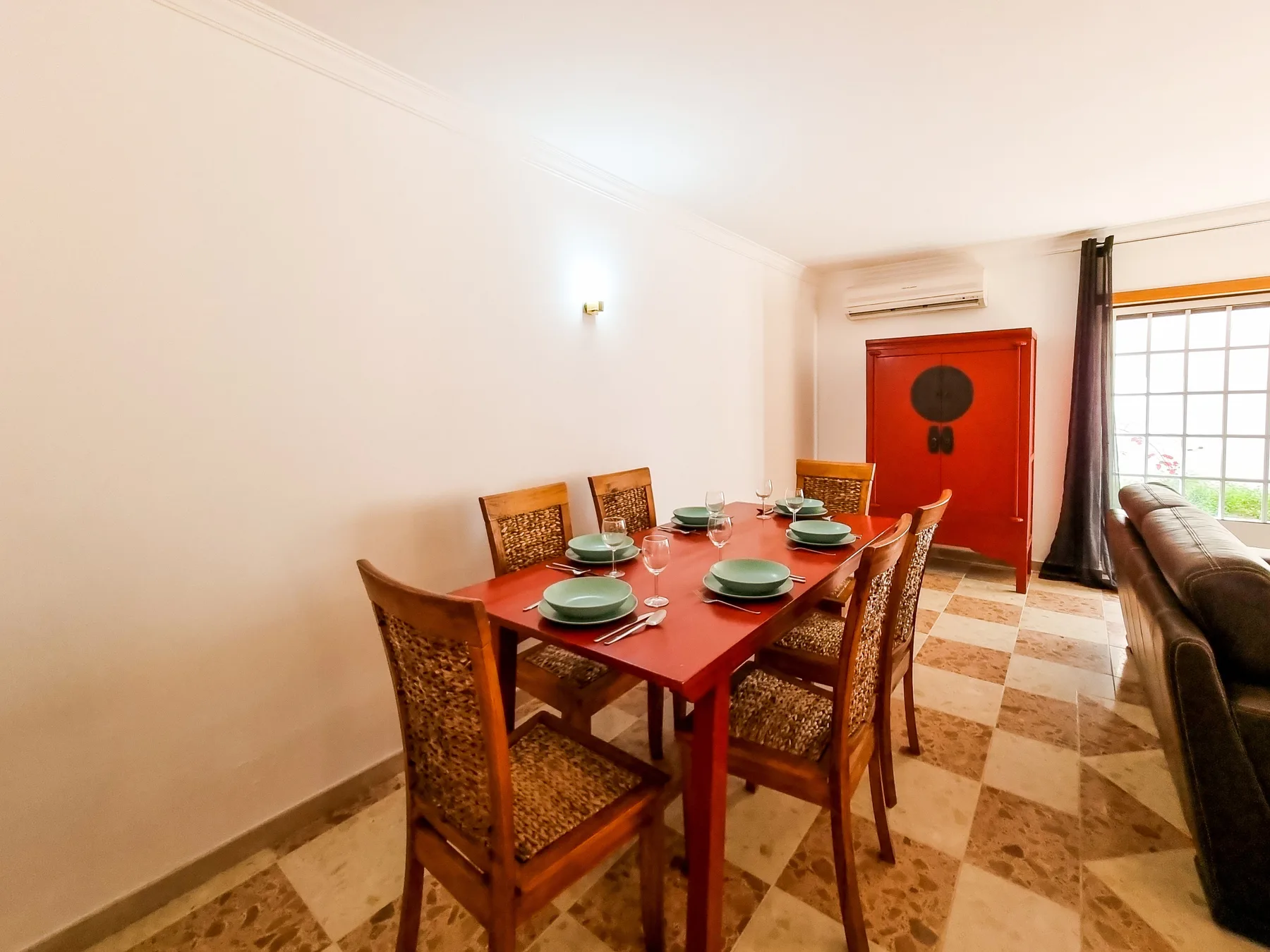 Comedor con una mesa de madera y sillas junto a una puerta roja.