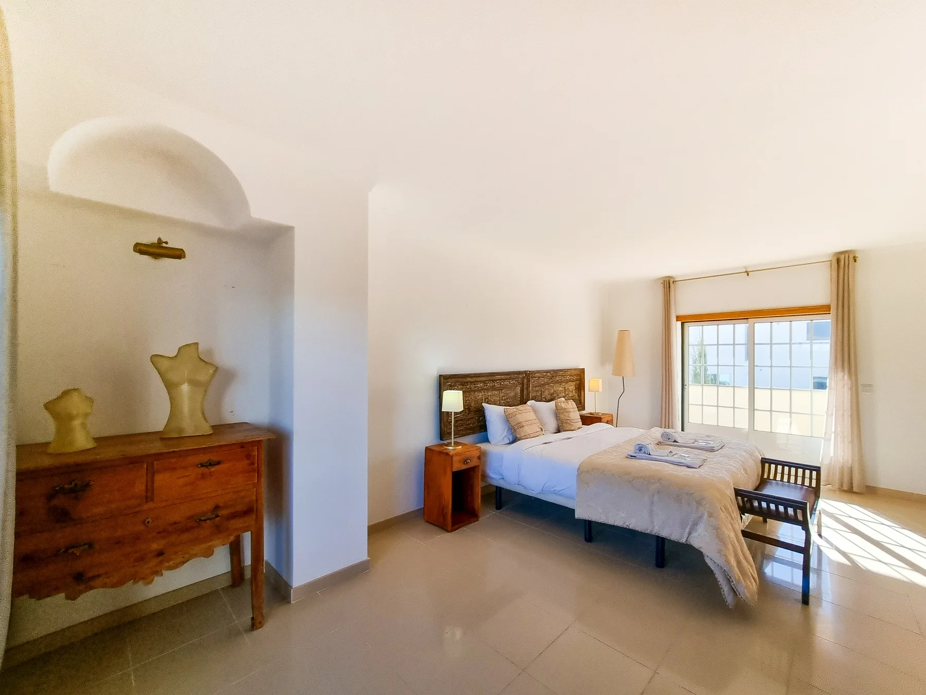 Un dormitorio con una cama, una mesa de noche y una ventana.