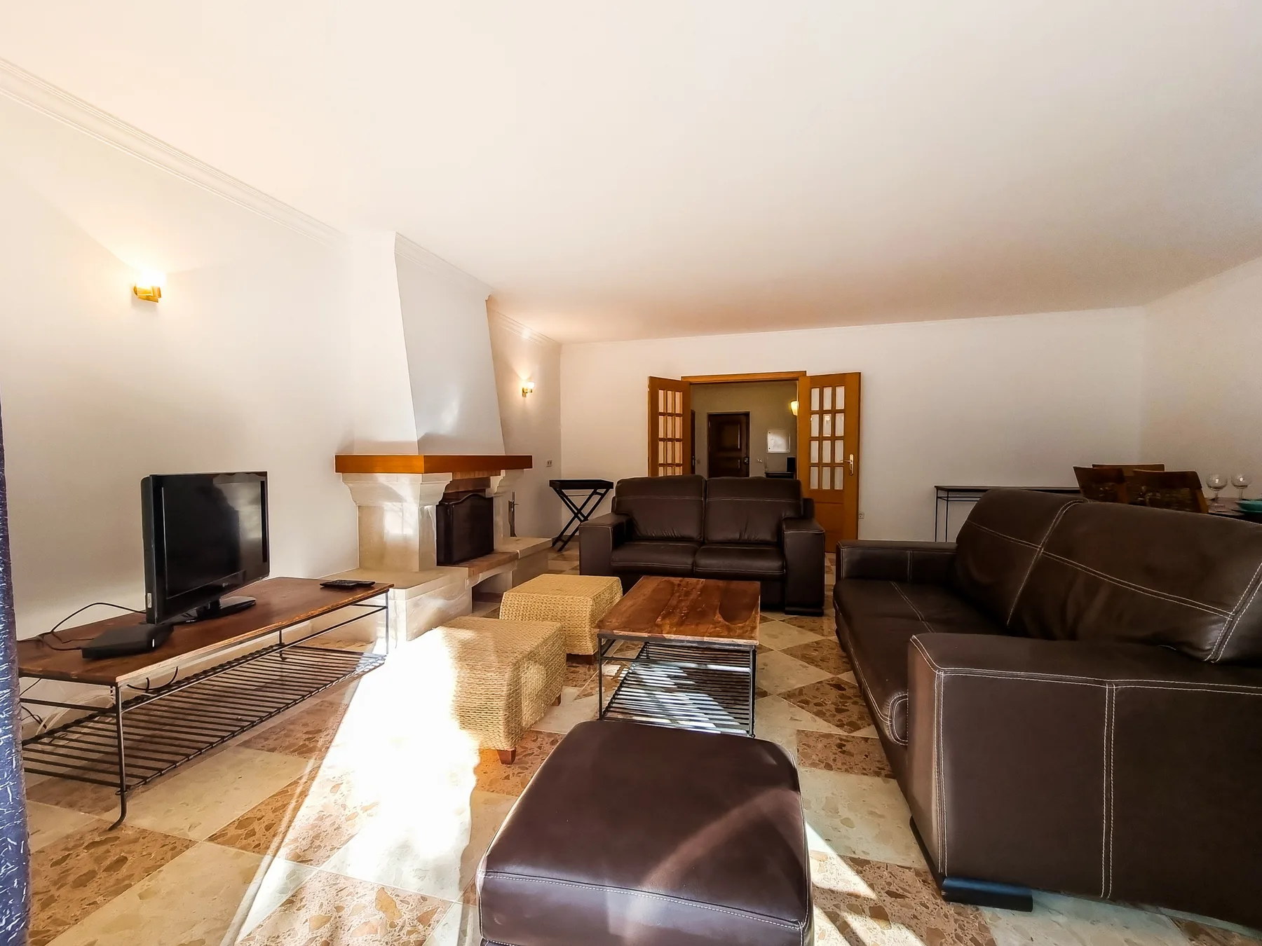 Una sala de estar con asientos oscuros, un televisor y una chimenea.
