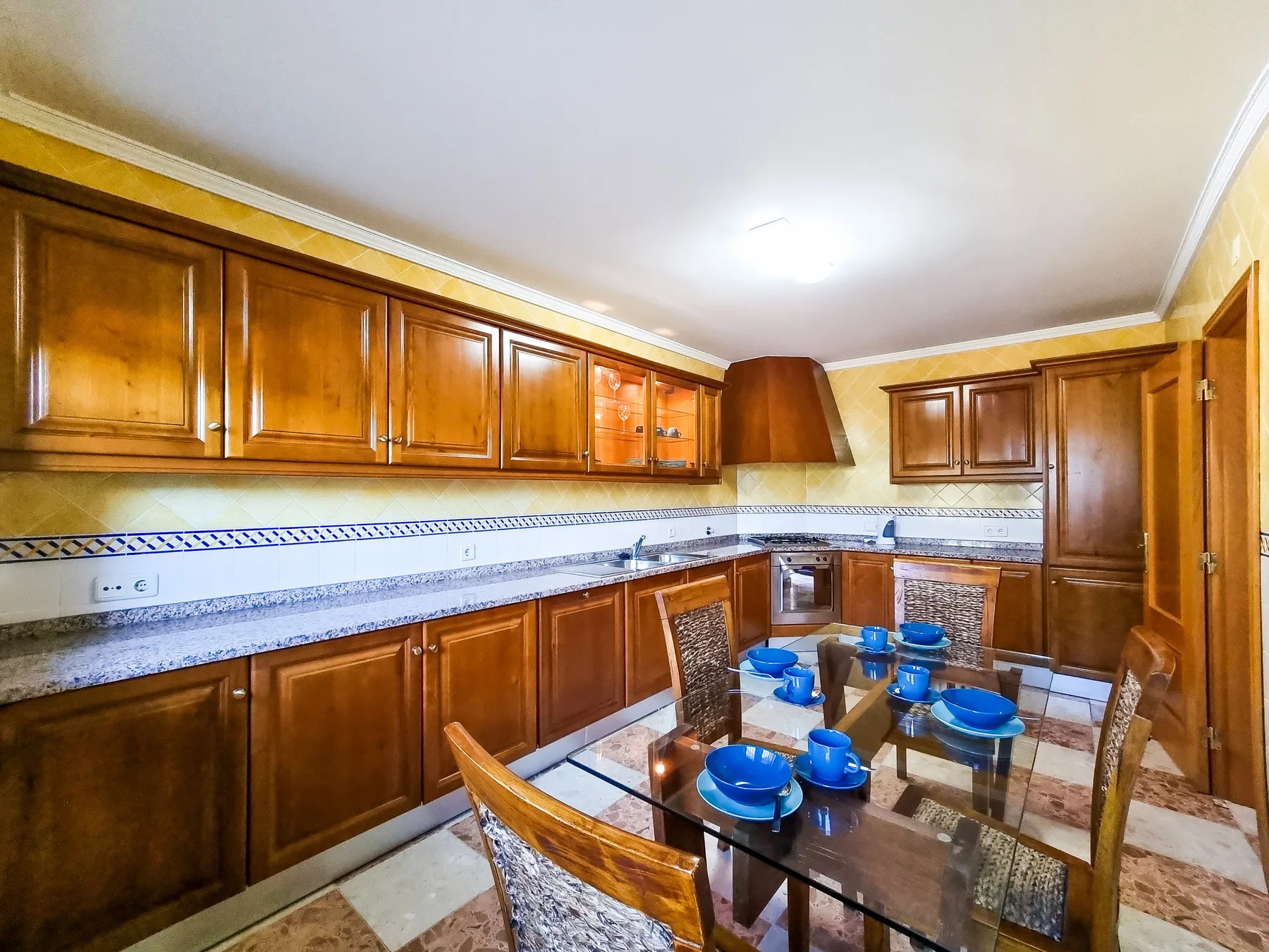 Una cocina con armarios de madera, una encimera y una mesa de comedor.