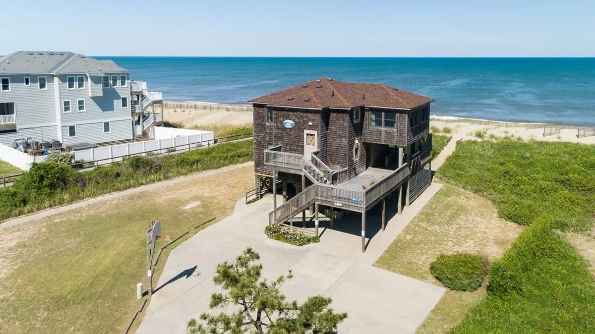 Coastal houses stand beside the beach, with the ocean stretching across the background.