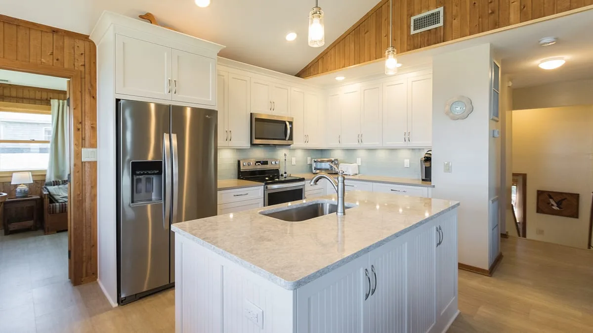 A bright kitchen with white cabinets, stainless steel appliances, and a central island.