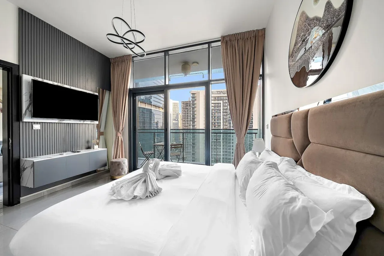 A bright bedroom with a large bed facing floor-to-ceiling windows.