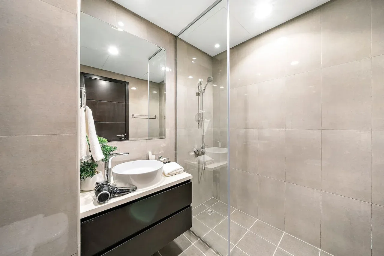 A tiled bathroom with a glass shower and a sink vanity.