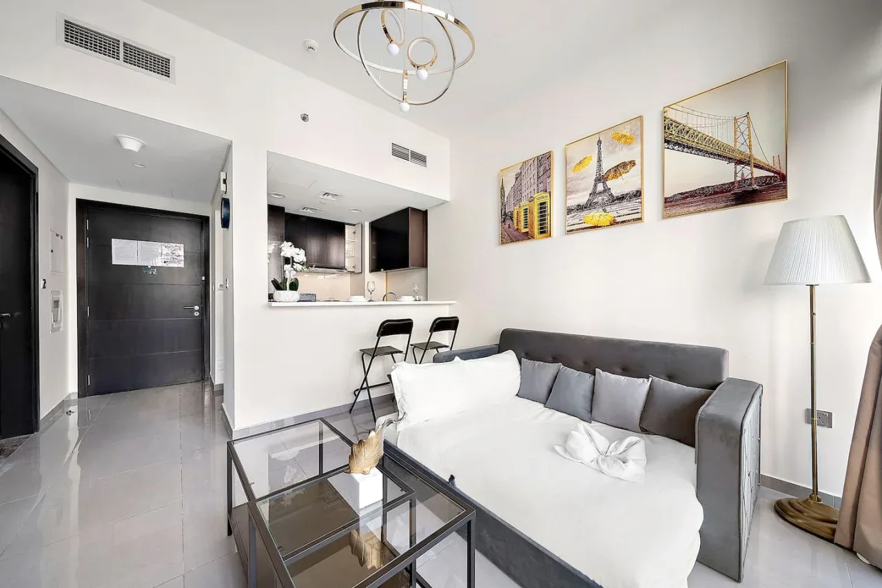 A bright living area with a gray sofa and a kitchen counter.