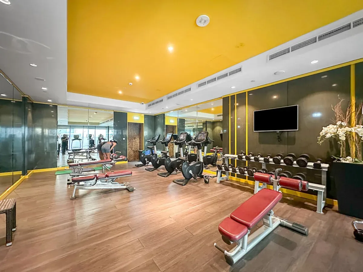 A gym with exercise machines, weight racks, and workout benches.