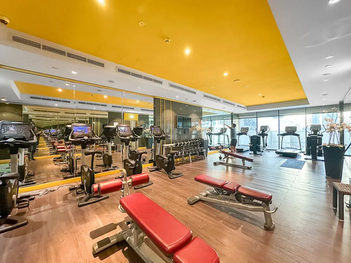 A gym with exercise machines, weight equipment, and red-padded benches.