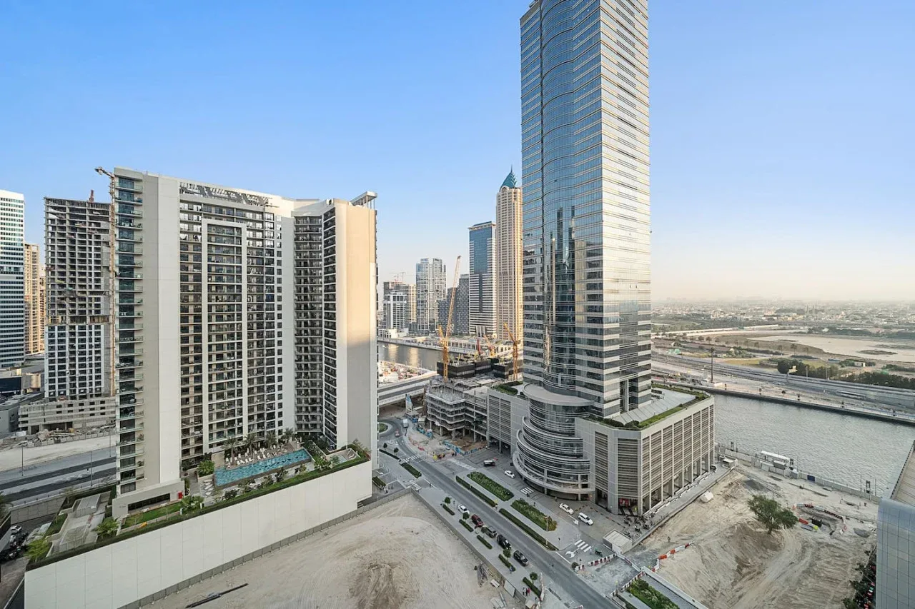 A cityscape of high-rise buildings beside a river and multilane roads.