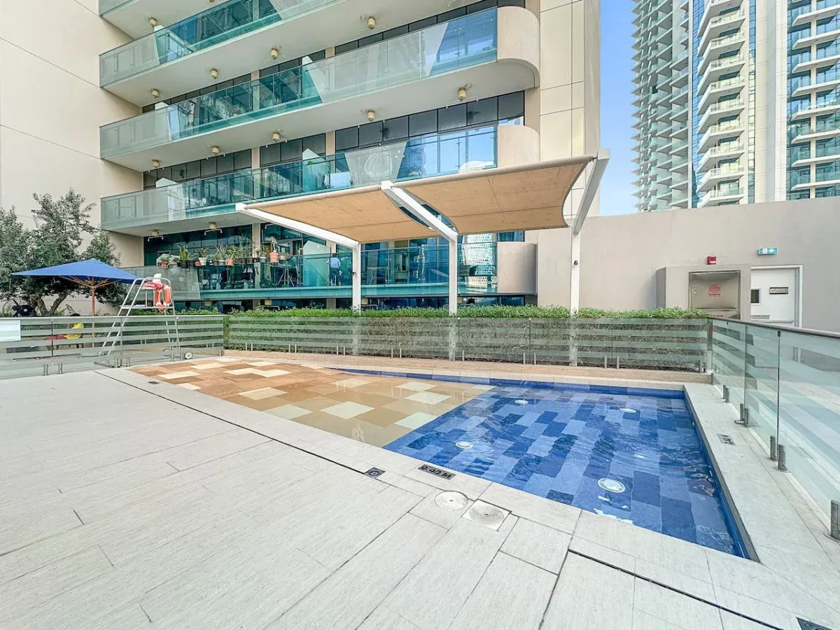 An outdoor swimming pool sits beside a modern high-rise building.