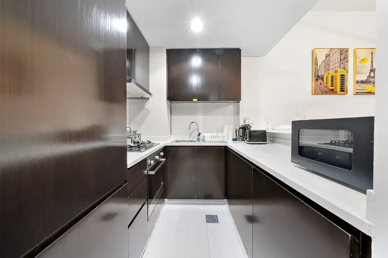 A modern kitchen with dark cabinetry, white counters, and built-in appliances.