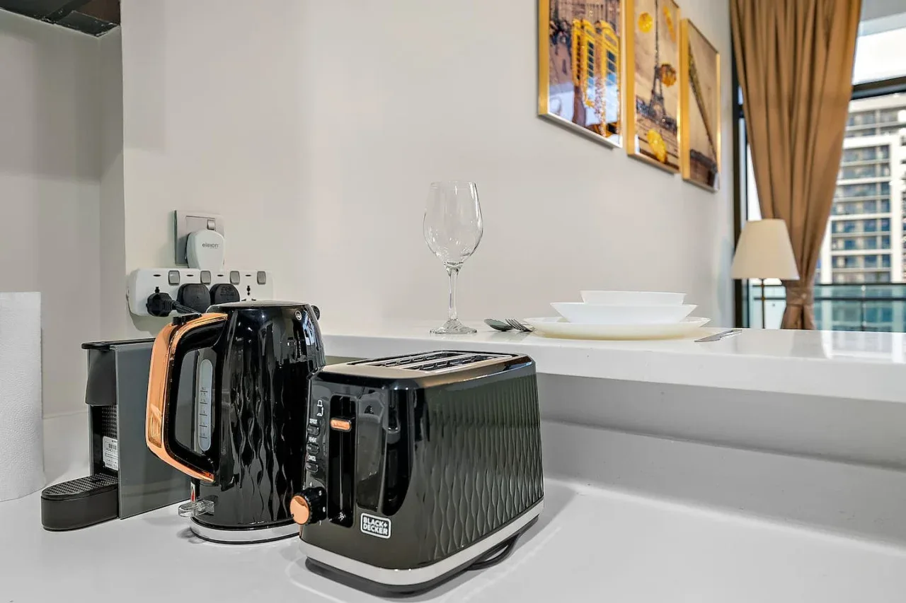 A kitchen counter holds a toaster beside a sink and a place setting.