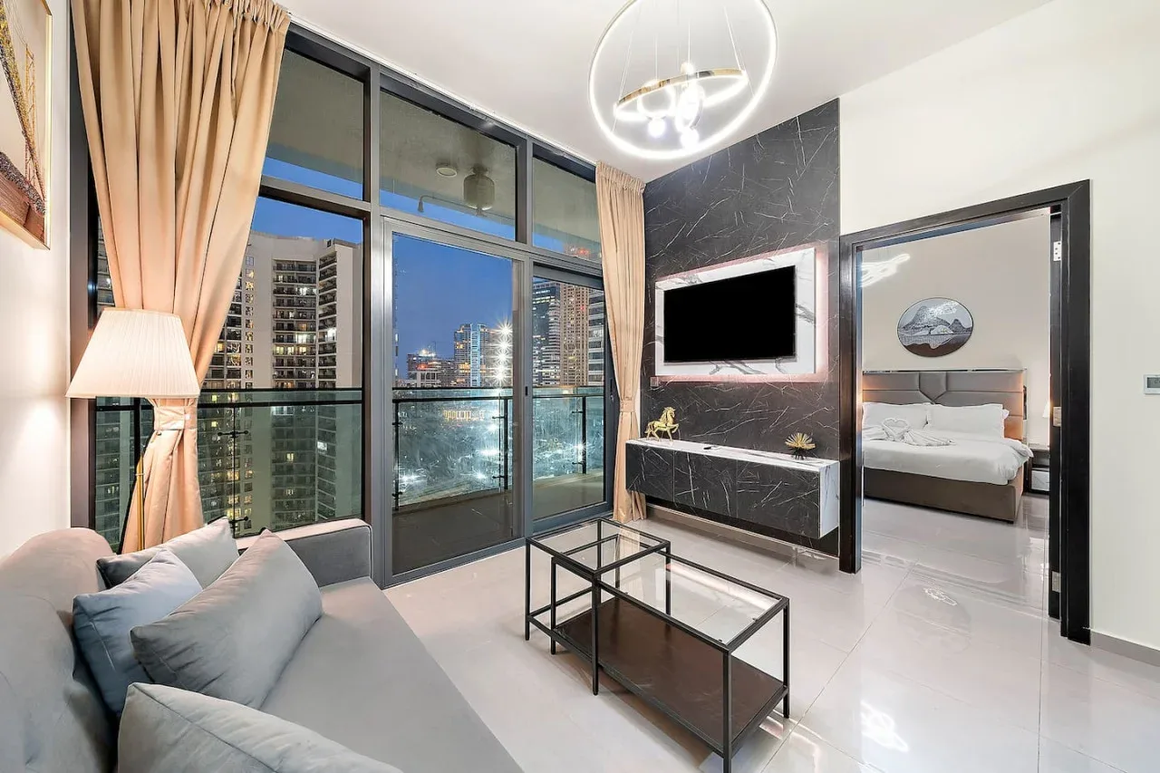 A modern living room with large windows, seating, and a view of the city.