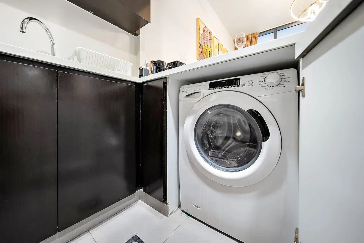 A compact laundry area with a front-loading washing machine beneath a counter.