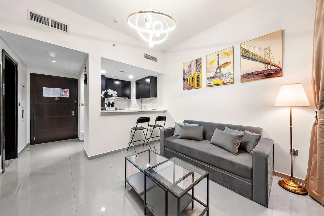 A modern living area with gray seating, a glass coffee table, and a breakfast counter.