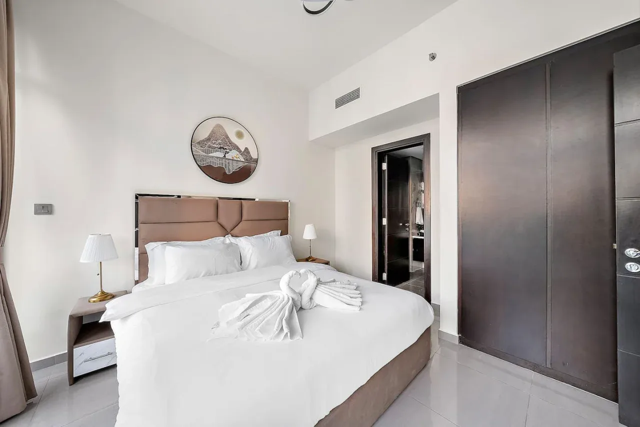 A bedroom with a neatly made bed and a dark wardrobe.