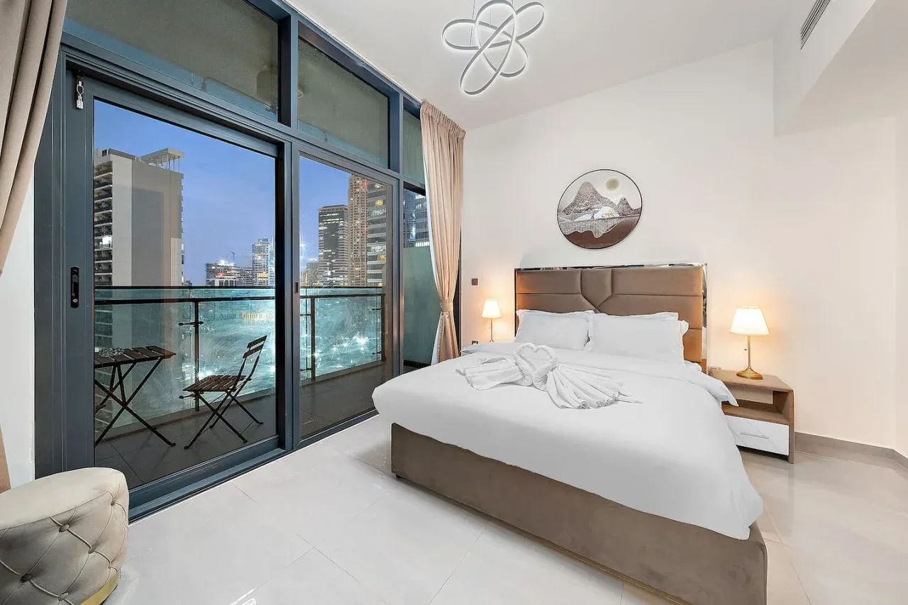 A bright bedroom with a large bed and glass doors opening onto a balcony.