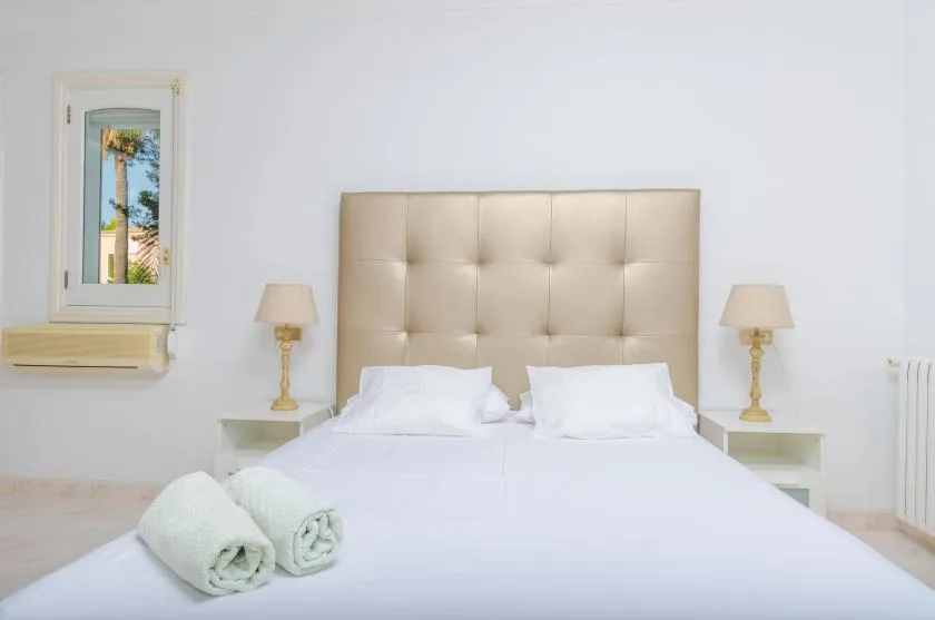 A bright bedroom with a double bed and bedside lamps.